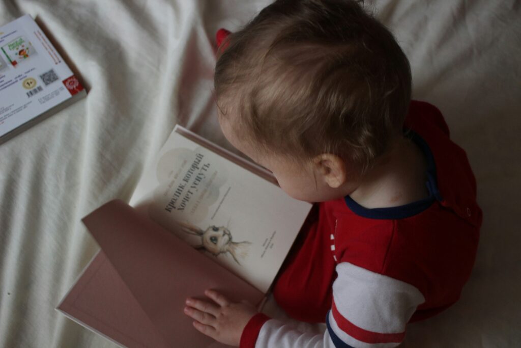 ベッドに座って本を読んでいる赤ちゃん