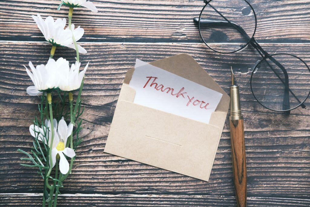 メガネとペンと花を横に添えた「ありがとう」の手紙